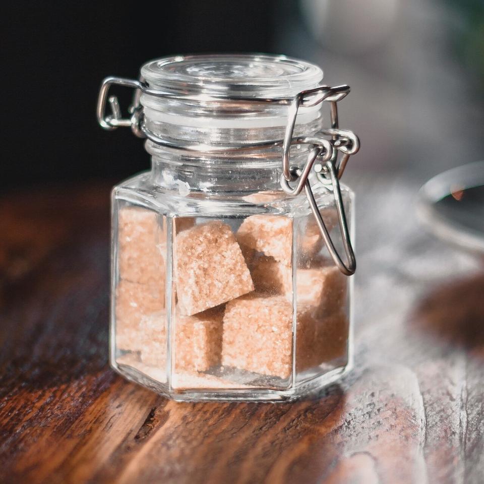 Vanilla sugar in a jar from Flavour World SA, with a spoon showing the fine, sweet vanilla-coated sugar crystals.